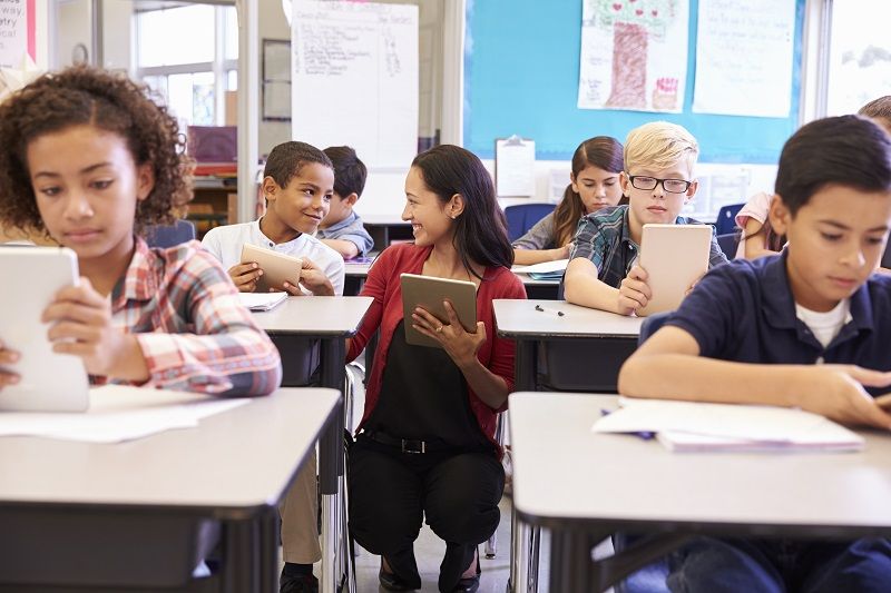 Comp Teacher among kids with computers in elementary school class