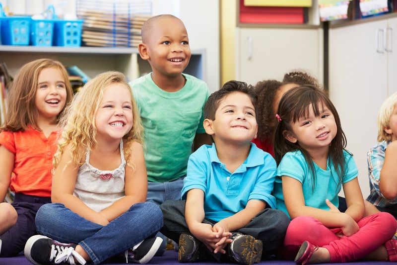 Group of elementary pupils having fun in classroom cm