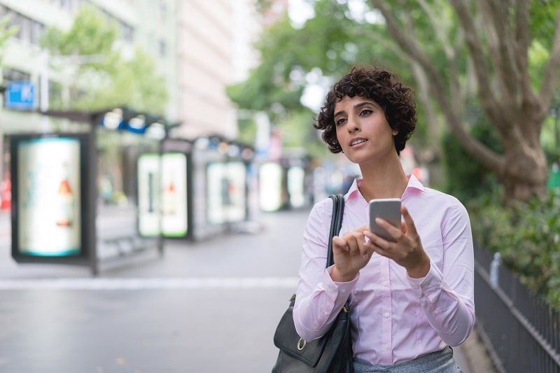 Business woman requesting a taxi on her cell phone