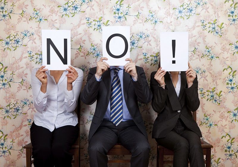 Three people holding the word NO over their faces cm