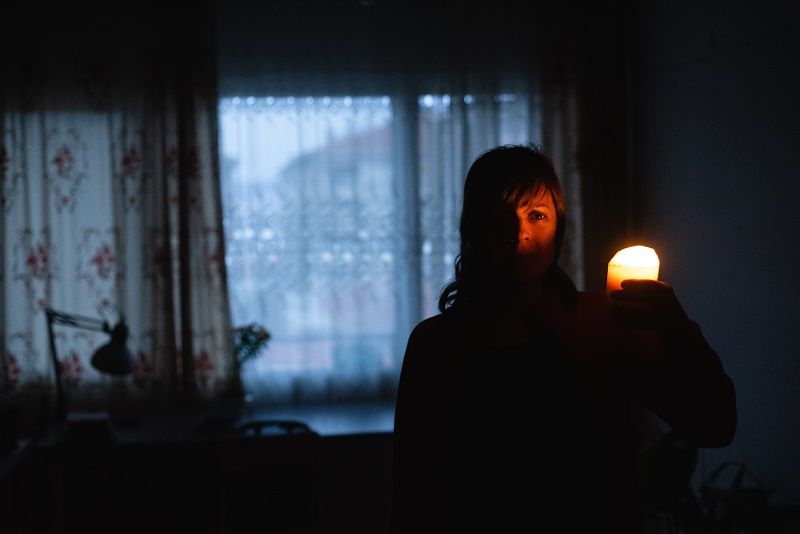 Woman with candle at home because of power cut cm