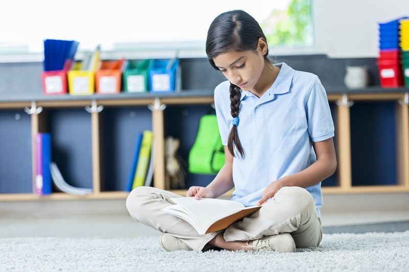 Hispanic middle school student reads book in classroom cm